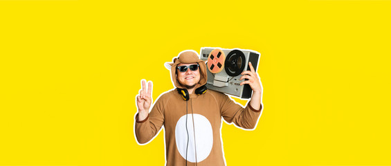 Man in cosplay costume of a cow with reel tape recorder isolated on yellow background. Guy in the...