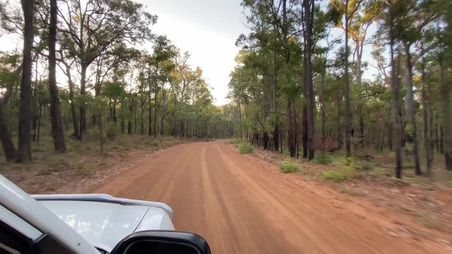 White SUV driving through Australian bush on dusty gravel road