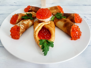 Pancakes with red caviar on a light background. Russian traditional dish.