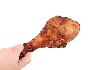 Close up and isolated image of hand holding a grilled chicken leg on white background.