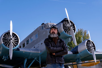 Middle-aged pilot, posing in front of a classic plane