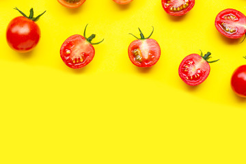 Fresh cherry tomatoes, whole and half cut isolated on yellow background.