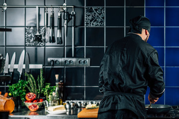 Male Chef from Behind, Peppering Food in a Kitchen