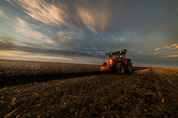 Tractor plowing fields in sunset