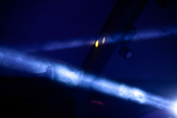 Blue beam of the stage spotlight in the dark, through the smoke