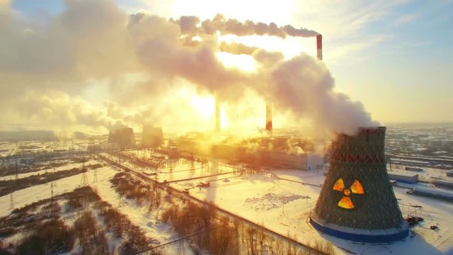 Aerial panoramic flight of hyperlaps around the nuclear power plant. Winter carbon dioxide emissions, Energy of smoke and steam, sun shines through clouds of smoke. Ecology and pollution of nature.