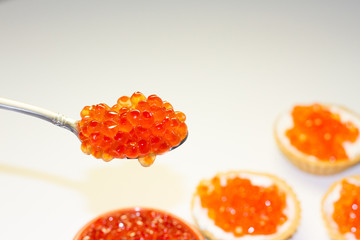 red caviar in a saucer with a spoon on a light table. the concept of a delicious Breakfast, buffet and snack. seafood dish. the view from the top. space for text.