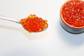 red caviar in a saucer with a spoon on a light table. the concept of a delicious Breakfast, buffet and snack. seafood dish. the view from the top. space for text.