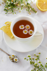 Delicate Provencal style still life with herbal tea and flowers. Hot tea with chamomile and lemon for the treatment or prevention of colds or flu using the folk method. Light, romantic photo.