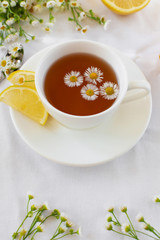Provencal style still life with herbal tea and flowers. Hot tea with chamomile and lemon for the treatment or prevention of colds or flu using the folk method. Light romantic photo.