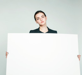 young pretty brunette girl with placard on white background wearing business costume student, lifestyle people concept