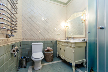 Spacious luxury bathroom with toilet, shower and washbasin. The walls are lined with expensive and beautiful tiles in blue and white colors. 