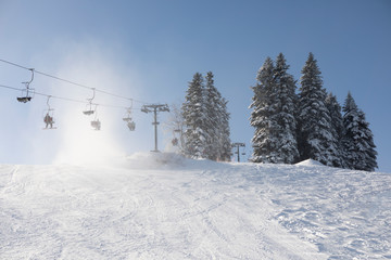 People are lifting on ski-lift in the mountains. Beautiful, sunny and windy weather.