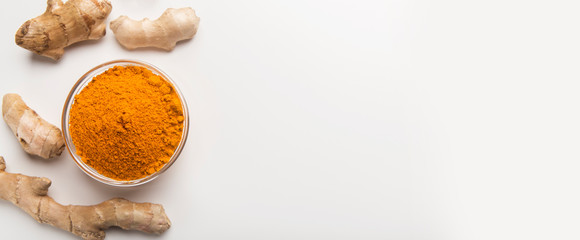 Turmeric roots with turmeric powder isolated on white
