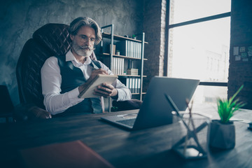 Focused minded old man real estate agent sit chair table note in copybook plan his work day...
