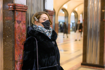 young european woman in protective disposable medical black mask in metro. concept protection of dangerous 2019-nCoV influenza coronavirus, mutated and spreading in China