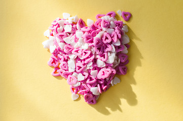 Heart shaped purple and white  confetti on a bright yellow background.