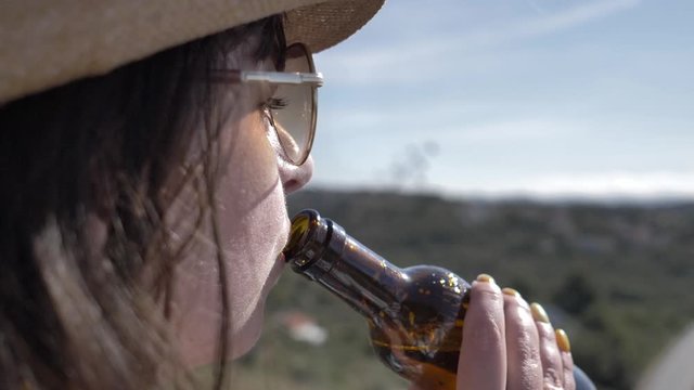 travel woman in hat and sunglasses drinks beer on the top