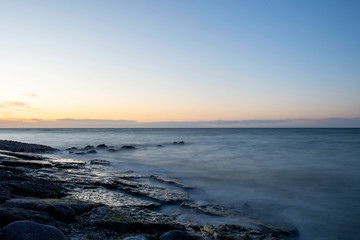 Fototapeta na wymiar Sundown over ocean with cobblestone beach in foreground, Sweden