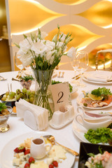 Table setting with meal and flowers on table, copy space. Place setting at wedding reception. Table served for wedding banquet in restaurant