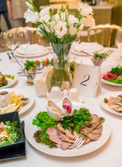 Table setting with meal and flowers on table, copy space. Place setting at wedding reception. Table served for wedding banquet in restaurant