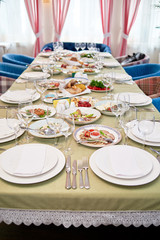 Table set with white plates, napkins , cutlery and wineglasses on table, copy space. Place setting at wedding reception. Table served for banquet in restaurant