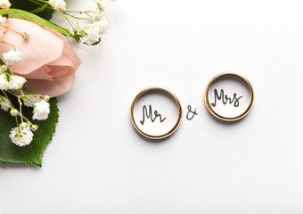 Engagement rings with text inside on background with cream roses