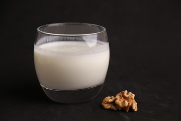 glass of walnut milk in color background