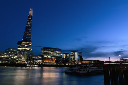 Illuminated London cityscape with River Thames at sunset