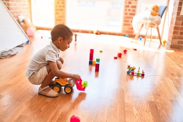 Beautiful african american toddler playing with tractor toy at kindergarten