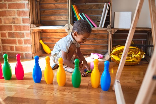 Beautiful african american toddler playing with cars and skittles at kindergarten