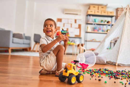 Beautiful african american toddler playing with small building blocks smiling at kindergarten