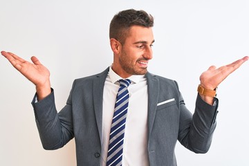 Young handsome business man wearing suit and tie over isolated background smiling showing both hands open palms, presenting and advertising comparison and balance