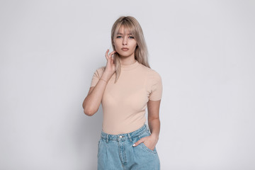 Sexy cute young blond woman in stylish clothes posing near a vintage white wall indoors. Beautiful...