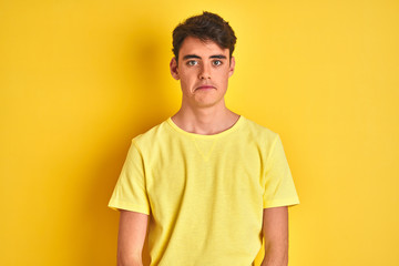 Fototapeta premium Teenager boy wearing yellow t-shirt over isolated background depressed and worry for distress, crying angry and afraid. Sad expression.