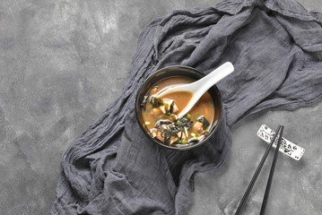 Japanese miso soup with fresh tuna, dried seaweed, tofu, shiitake dried mushrooms in a wooden bowl on the wooden background