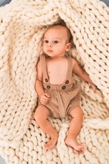 Adorable baby lying down over blanket on the sofa at home. Newborn relaxing and resting comfortable