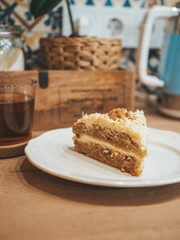 A piece of carrot cake with cottage cheese cream on the background of kitchen accessories, beautiful layout, kitchen design, decor