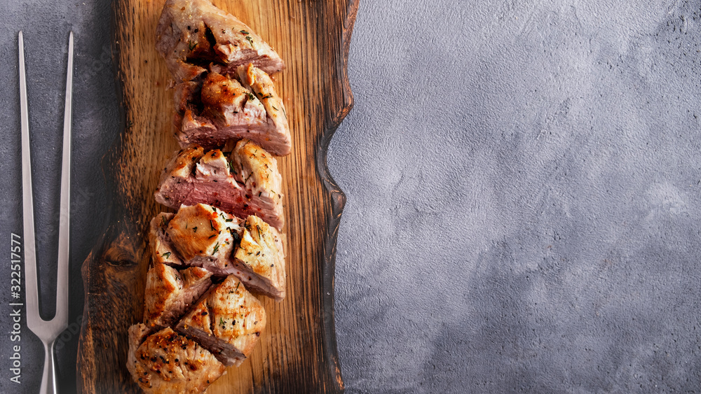 Wall mural delicious sliced meat tenderloin on wooden cutting board with copy space. top view