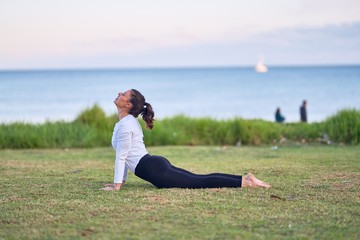 Fototapeta premium Young beautiful sportwoman practicing yoga. Coach teaching upward-facing dog pose at park