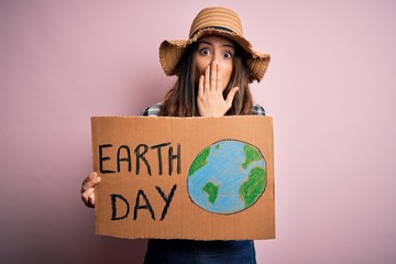 Young beautiful woman asking for planet conservation holding cardboard celebrating earth day cover...