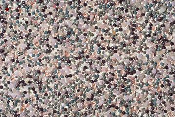 Texture of various jewels on a white background. Gray, brown and pink stones. Beads and necklaces are glued to the wall.