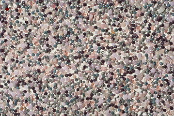 Texture of various jewels on a white background. Gray, brown and pink stones. Beads and necklaces are glued to the wall.