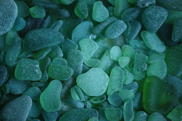 Serie di pezzi di vetro verdi logorati dal mare