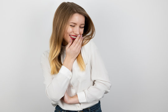 young beatuiful blond woman laughts looking shy standing on isolated white background, splash of emotions