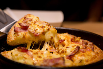 Hot pizza slice with melting cheese on a  table in restaurant pizza Italian food.