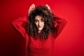 Young beautiful woman with curly hair and piercing wearing casual red sweater Doing bunny ears gesture with hands palms looking cynical and skeptical. Easter rabbit concept.