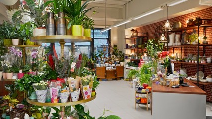 Beautiful atmospheric flower shop with decorations. Stylish interior design with plants, pots, and furniture 