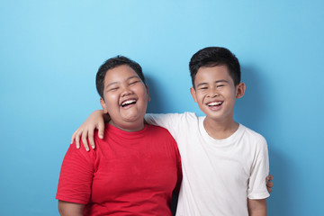 Two Asian boys looking at camera, smiling and laughing, best friends happiness