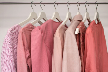 set of women's clothing of pink color in different colors on hangers, a concept for fashion and shopping